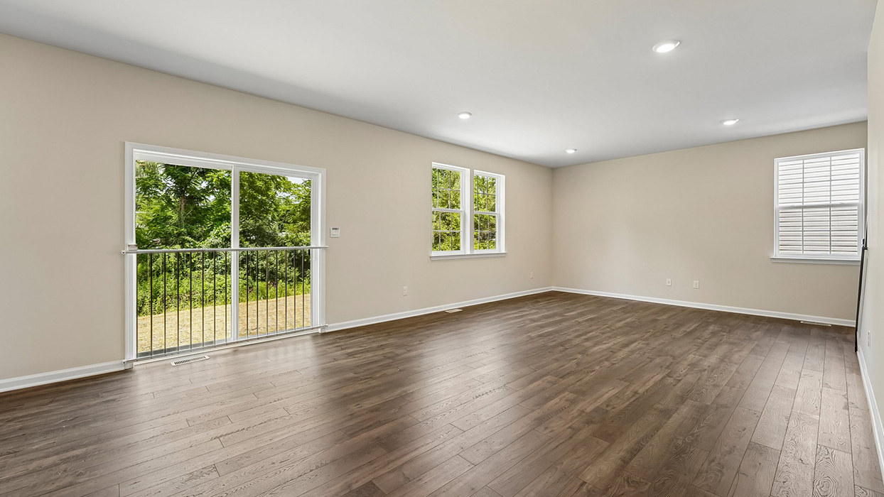 Spacious family room with large windows, sliding glass door, and abundant natural light overlooking backyard