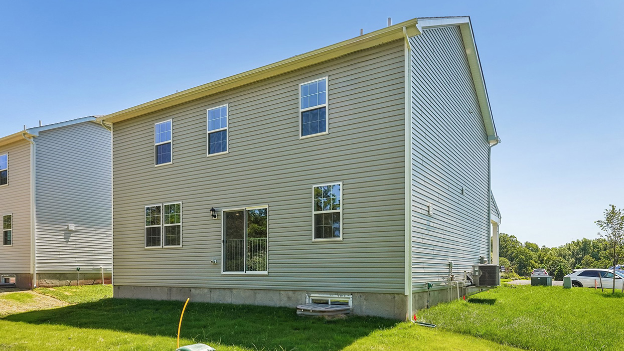Rear exterior of Galen home with G5 elevation, featuring sliding glass door, multiple windows, and backyard lawn space in Creekside Village