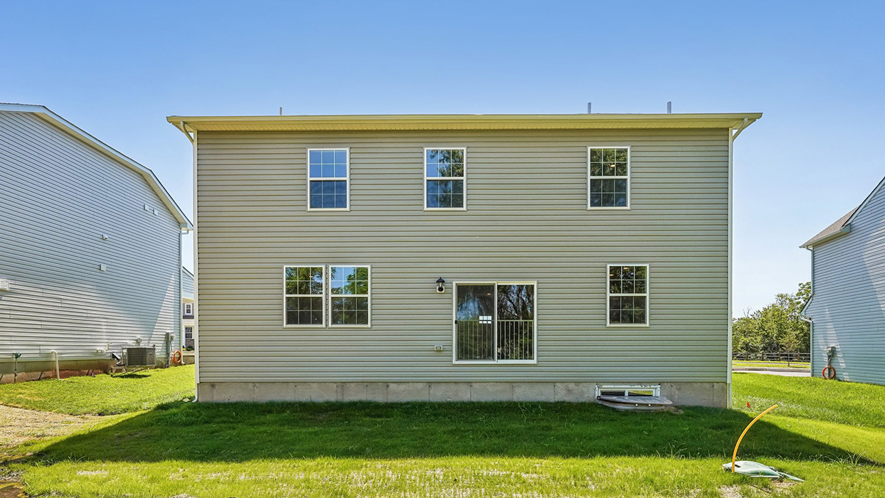 Straight-on rear exterior with sliding glass door, evenly spaced windows, and open backyard area for outdoor living