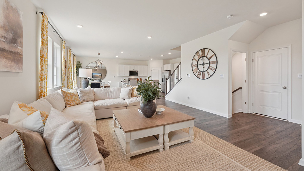 Living room with a large sectional sofa and coffee table facing backwards towards the open-concept kitchen and dining.