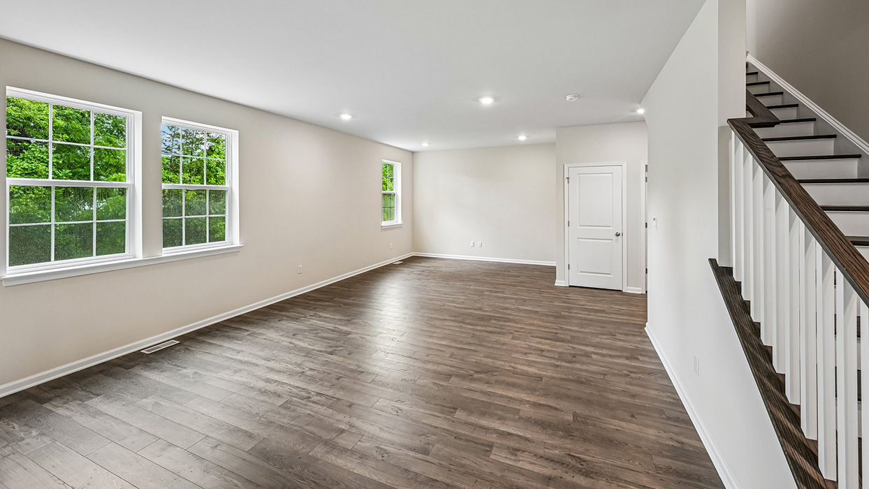 Living room with wood-look flooring, recessed lighting, and multiple windows providing natural light
