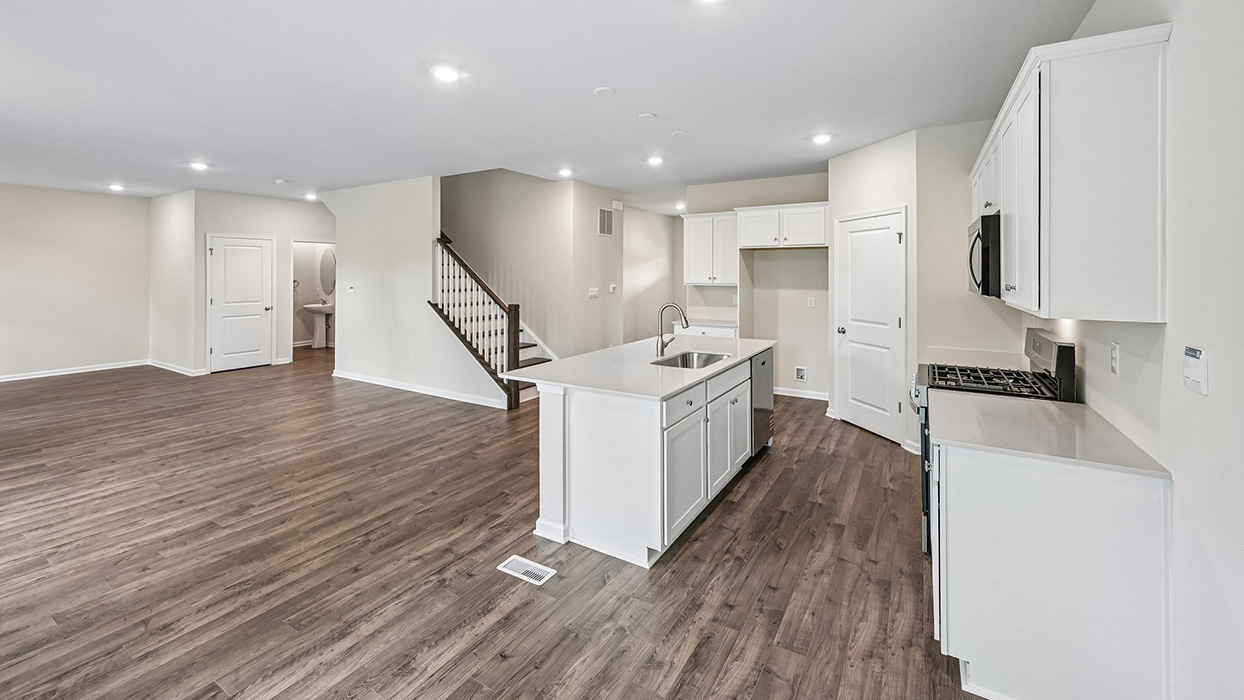Kitchen overlooking living space with island seating, pantry door, and staircase nearby