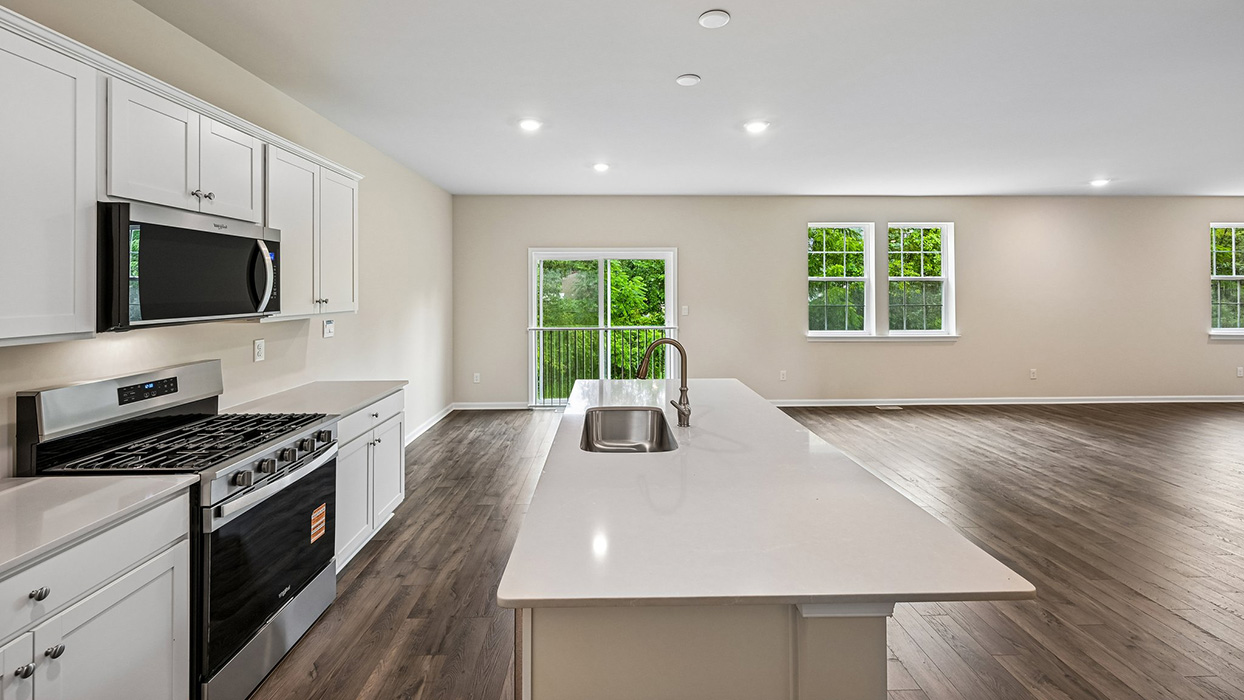 Kitchen island with sink and seating space, stainless steel range, and open view to living area