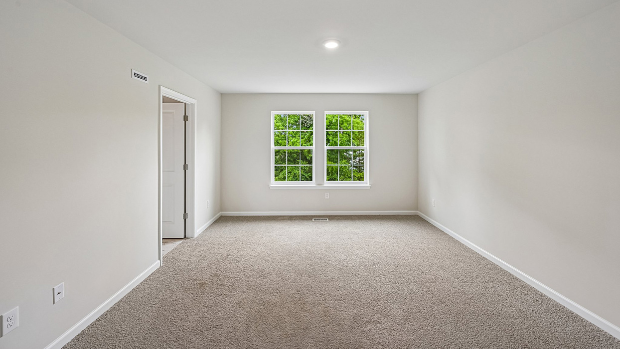 Primary bedroom with neutral carpet, double windows, and ensuite bathroom access