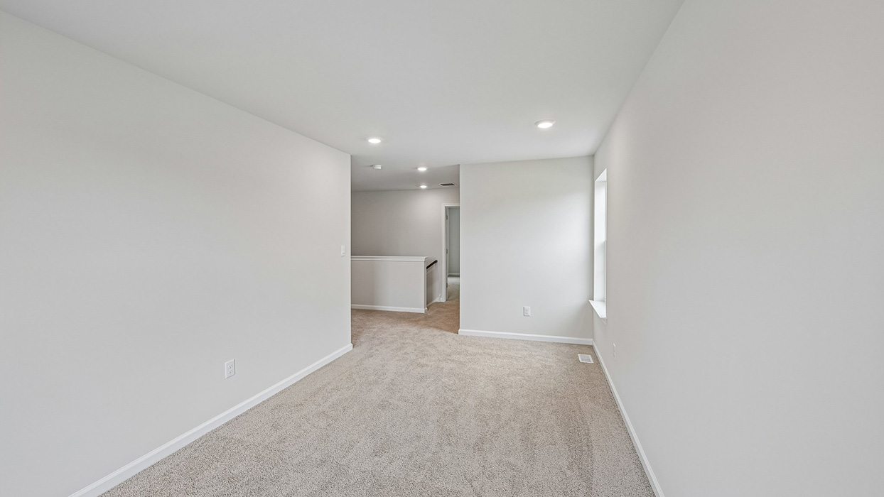 Second-floor bonus living space with extended layout, carpet flooring, and window for natural light