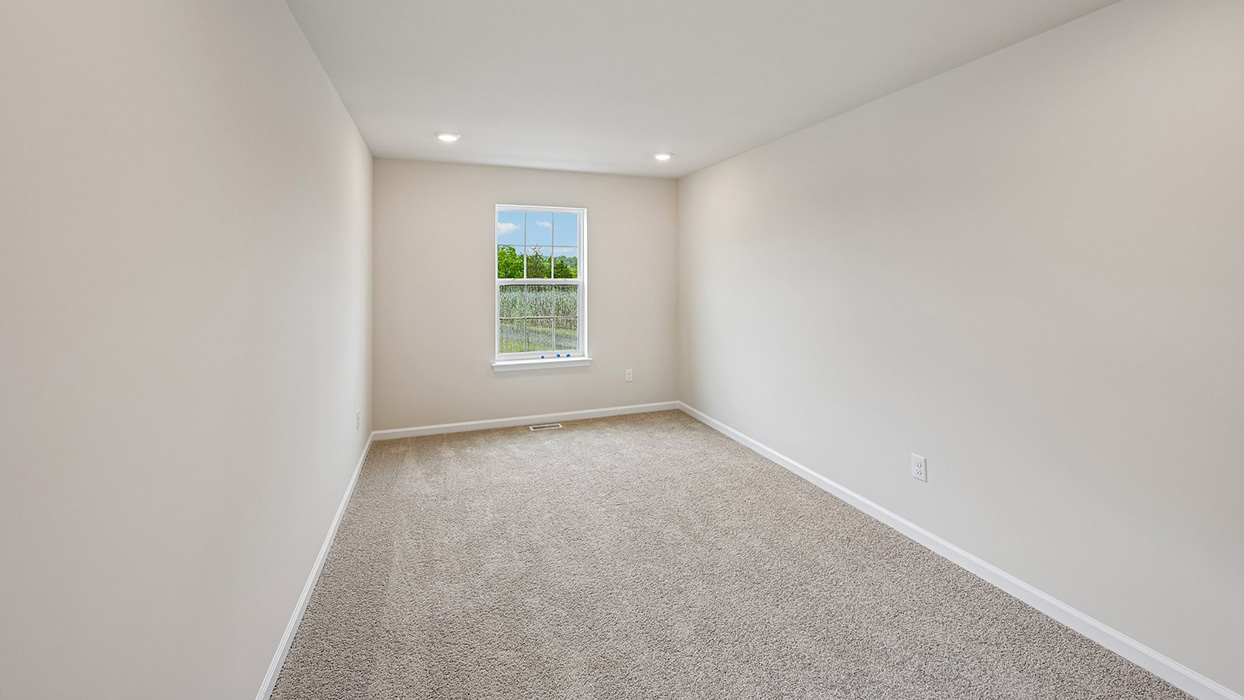 Upstairs loft or flex space with carpet flooring and partial wall overlooking staircase