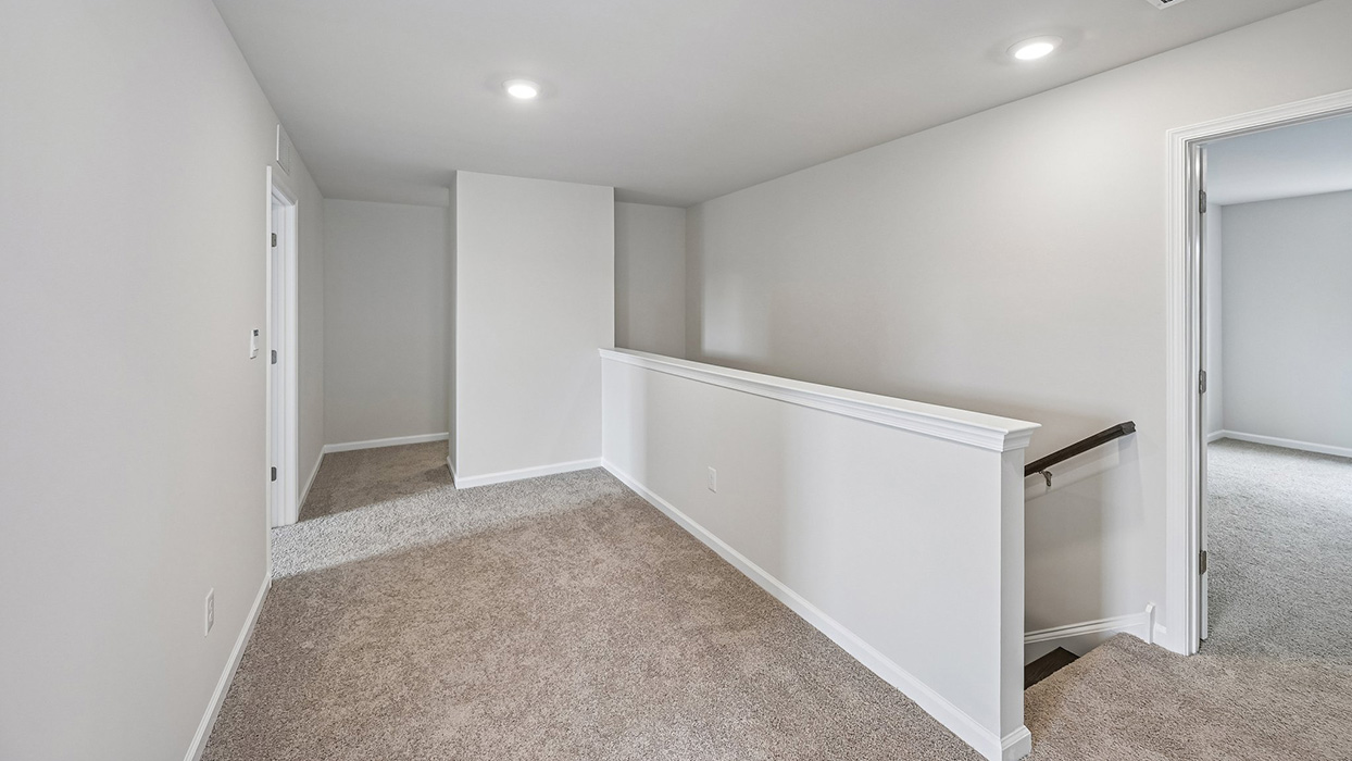 Upper hallway with railing overlooking stairs and access to adjacent bedrooms