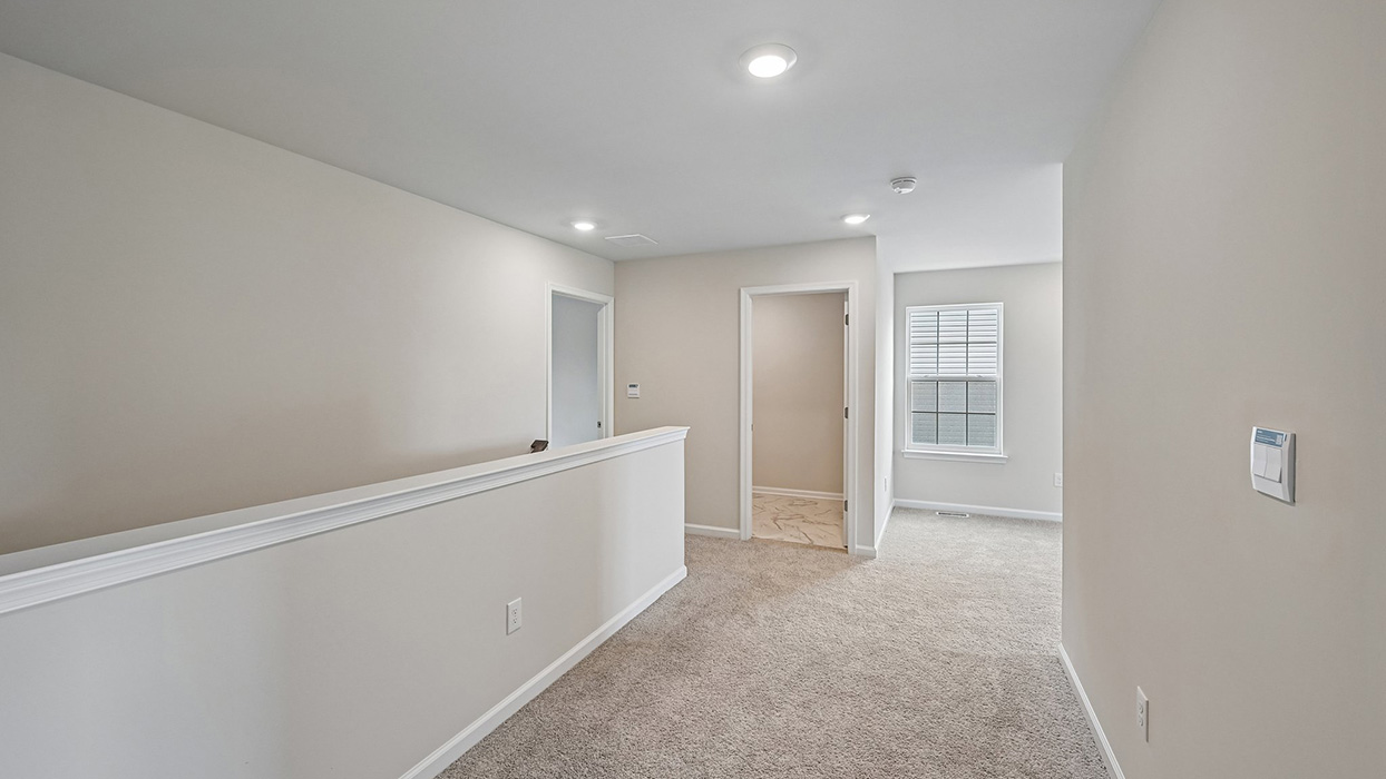 Second-floor hallway with carpet flooring, recessed lighting, and entry to bathroom and bedroom