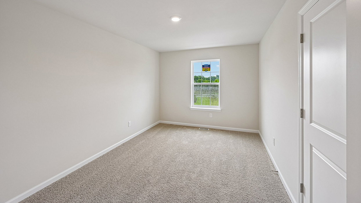 Bedroom with neutral carpet, single window for natural light, and clean white trim