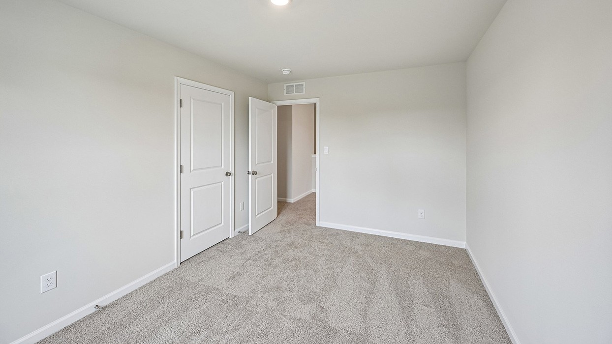 Bedroom with carpet flooring, double doors, and open view to hallway