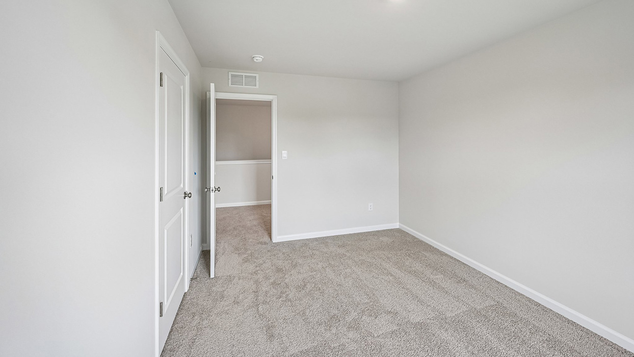 Secondary bedroom with soft carpet, neutral walls, and doorway to hall