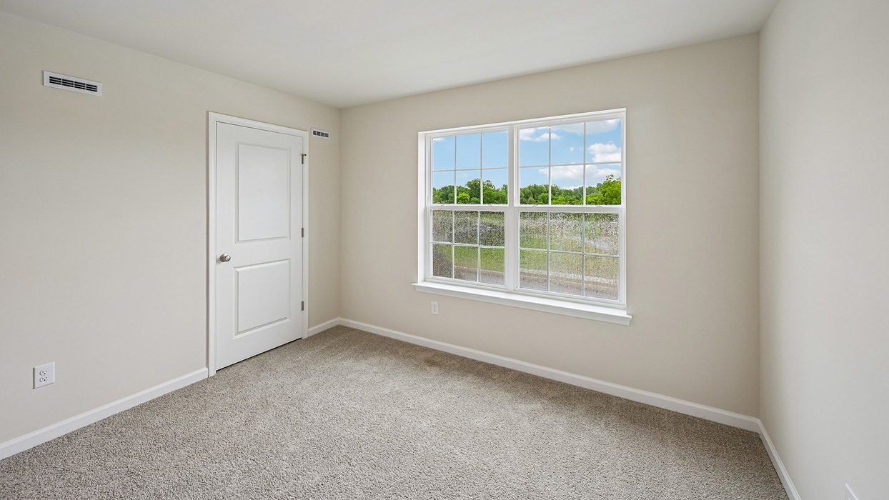 Secondary bedroom with dual windows, carpet flooring, and closet door