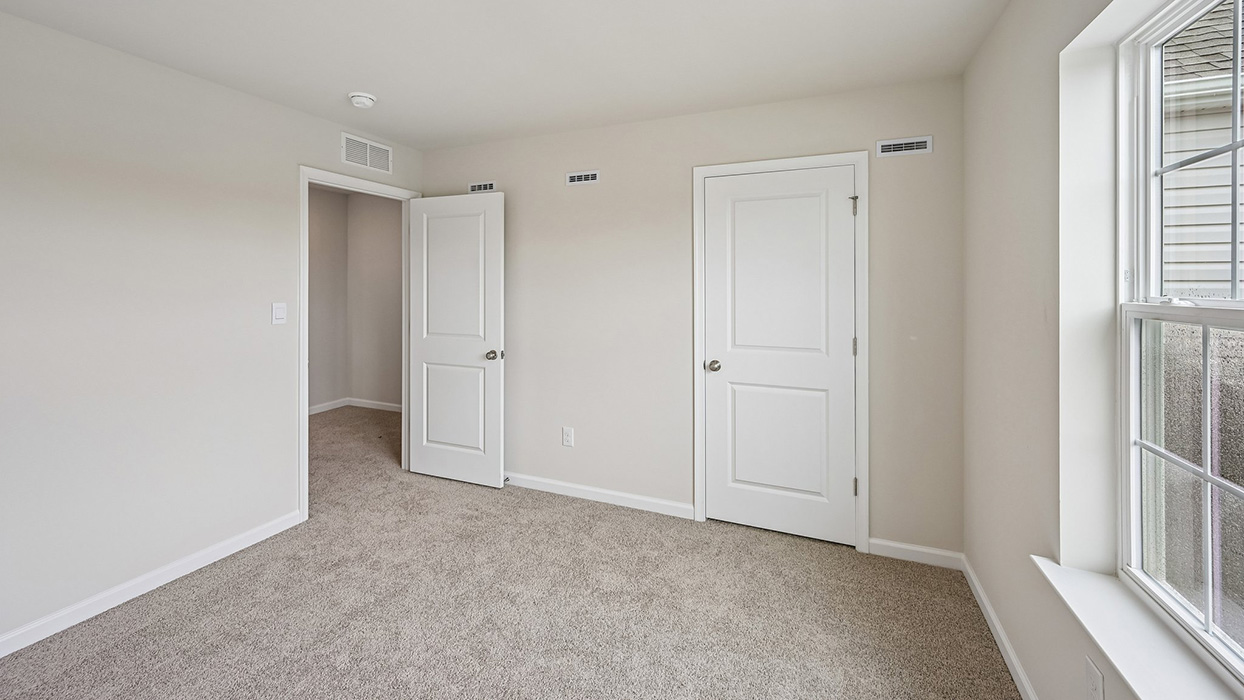 Bedroom featuring double-door closet, carpet flooring, and hallway access