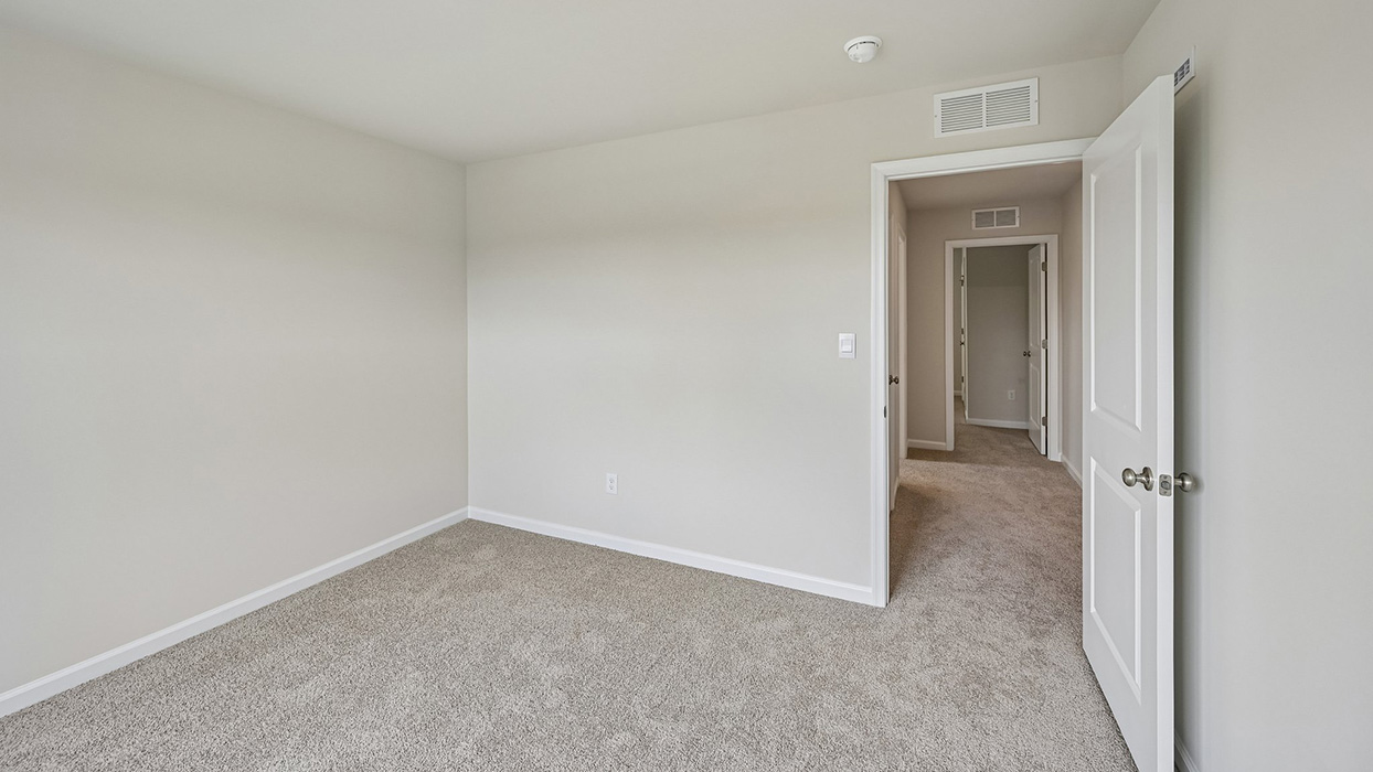 Secondary bedroom with neutral carpet, recessed lighting, and open doorway