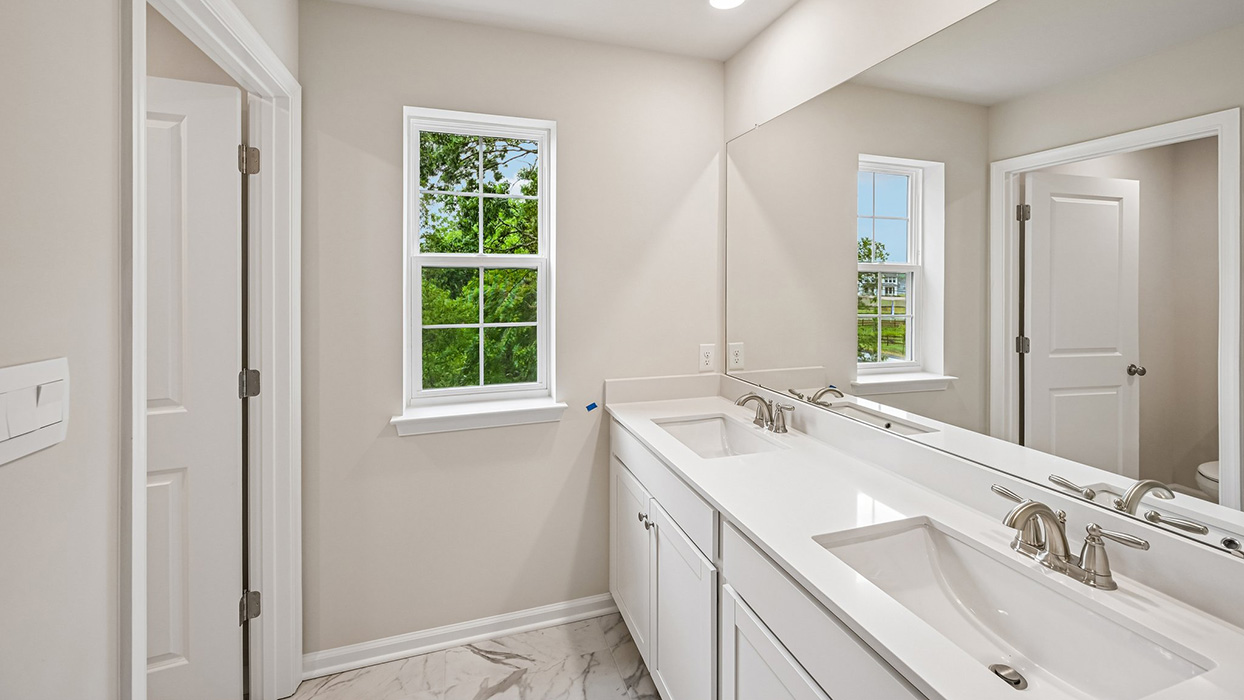 Full bathroom with double vanity, large mirror, and window for natural light