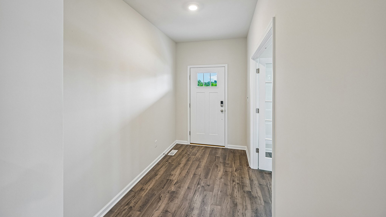 Entry hallway with wood-look flooring, neutral walls, and front door with window detail