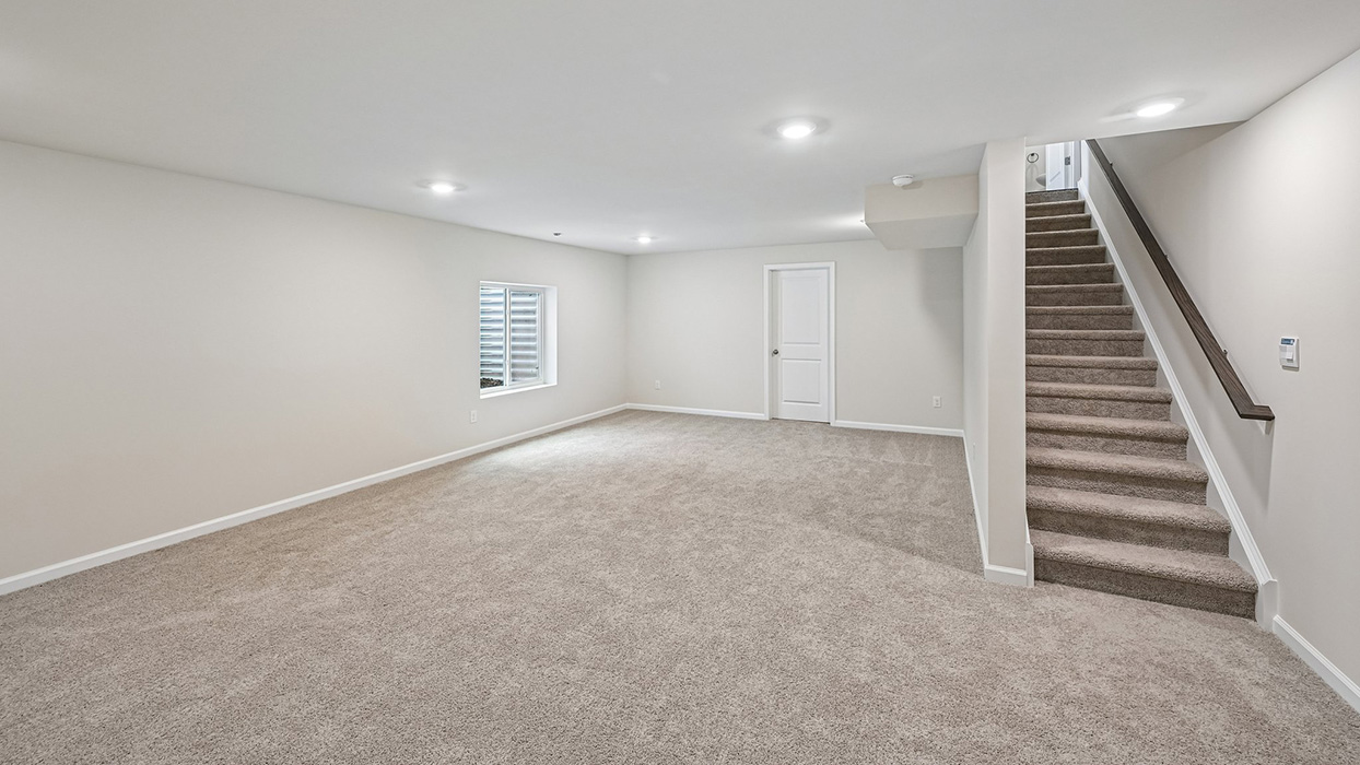 Finished basement recreation area with carpet flooring, recessed lighting, and stair access