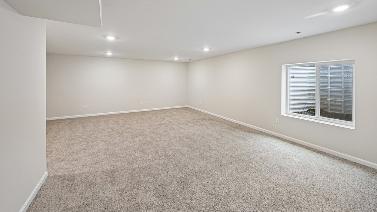 Spacious finished basement with open layout, recessed lighting, and egress-style window