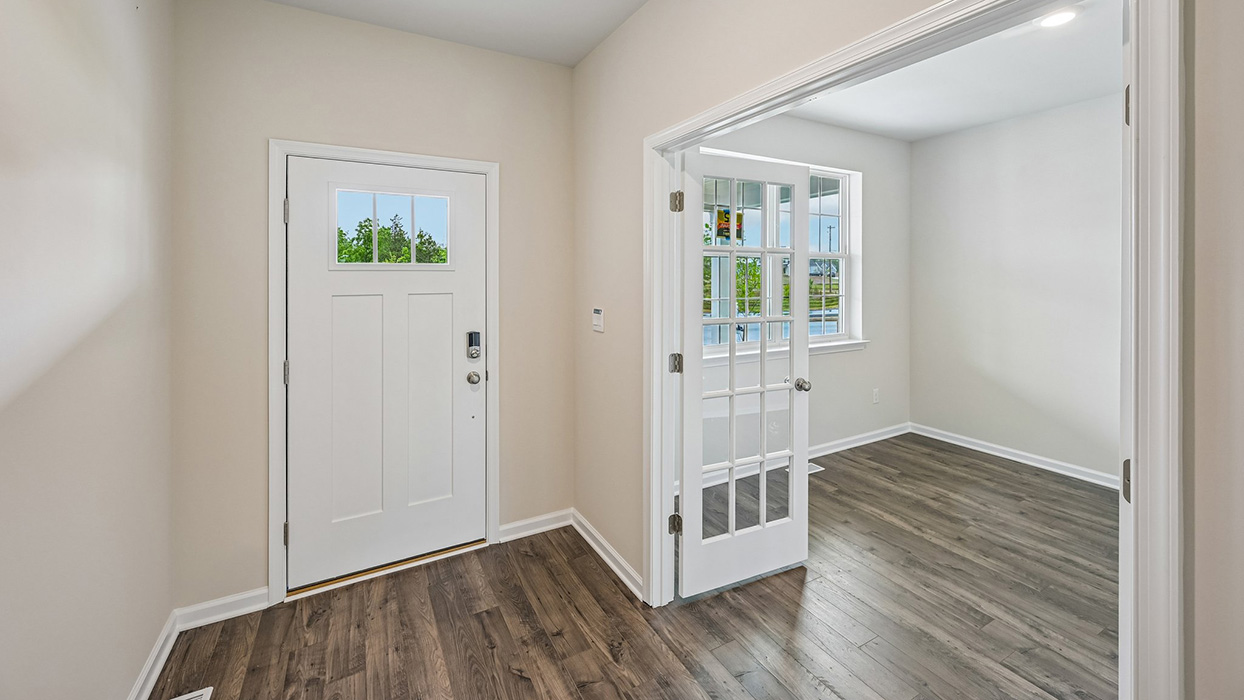 Foyer view showing front entry and adjacent flex room with glass doors
