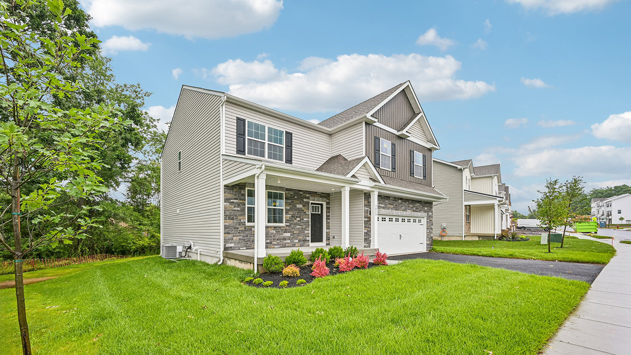 Side perspective of home showing covered porch, front landscaping, and spacious corner lot setting