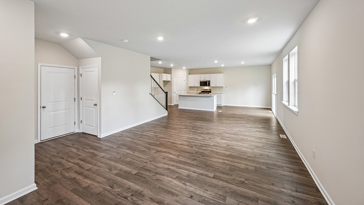 Wide view of open living and kitchen area with island seating and recessed lighting