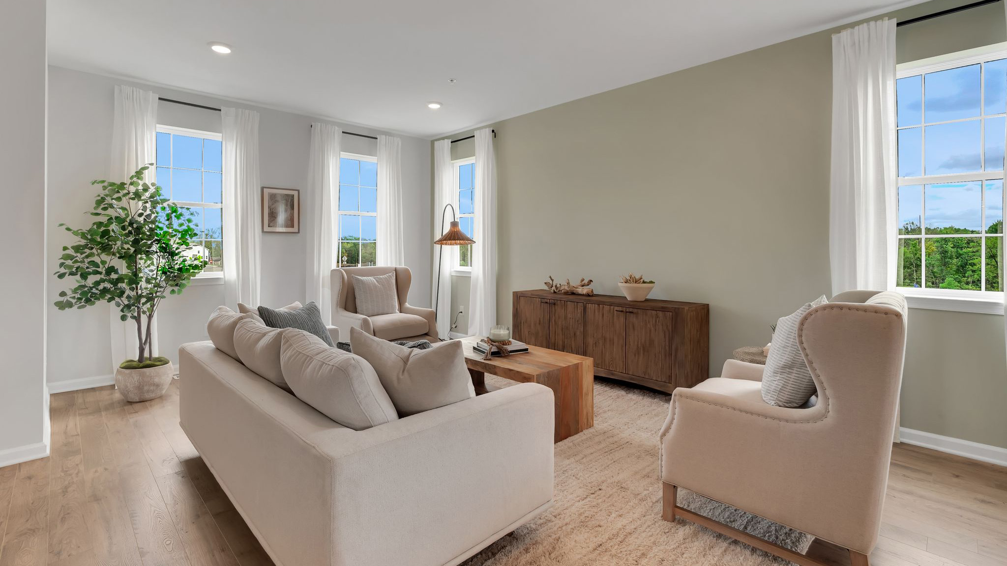 Living area with stair cases behind. A set of two single windows are on either wall.