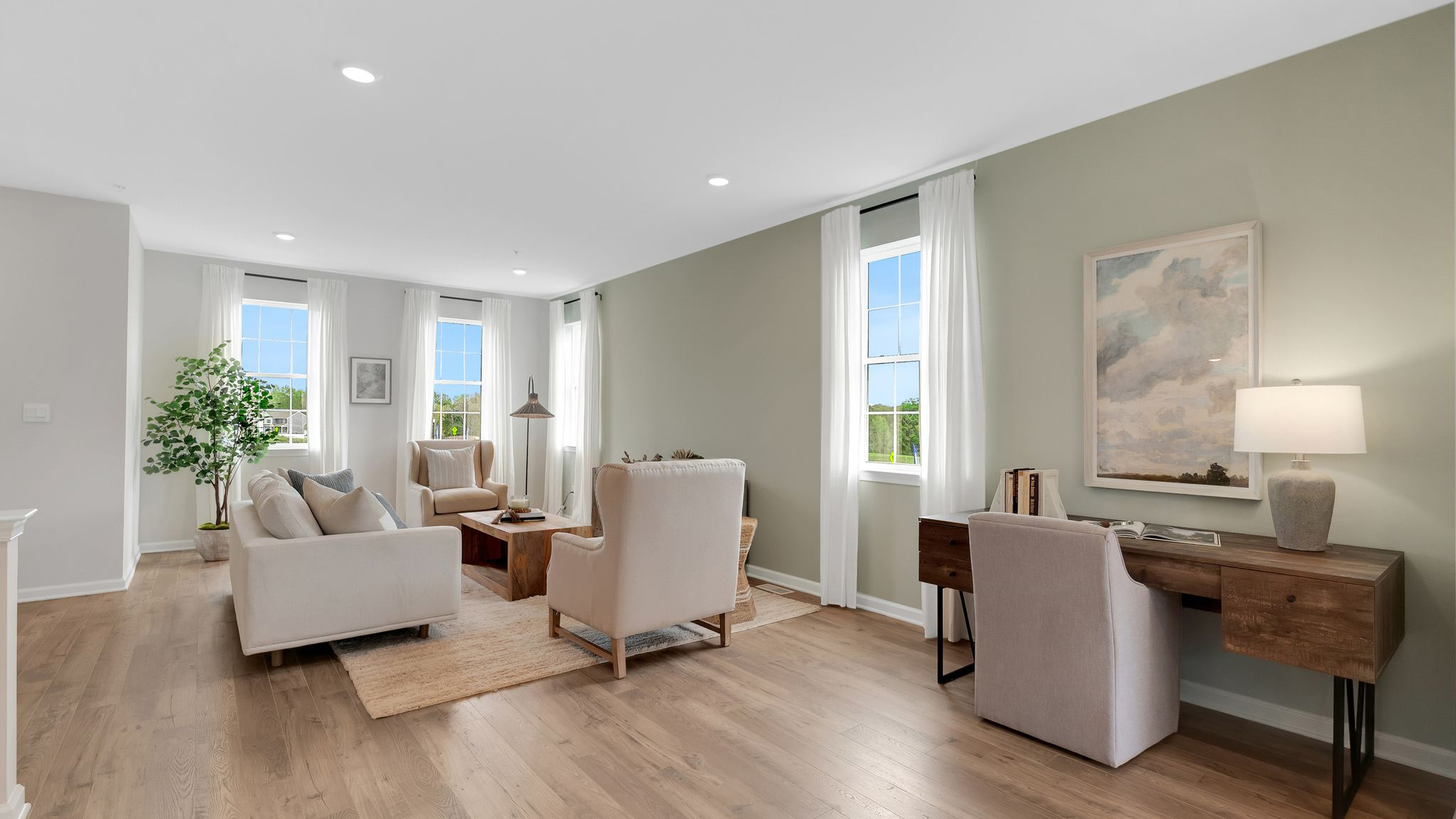 To the left of the kitchen island a wide view shot of the desk and living area.