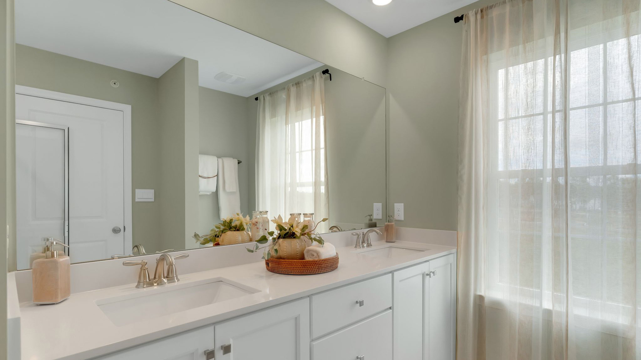 Bathroom that's connected to the third floor bedroom. Double sink white vanity and counter top and large window.