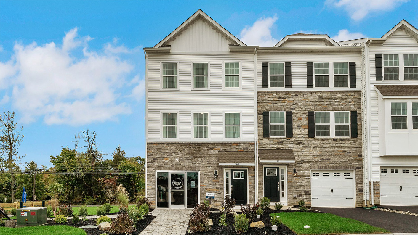 Exterior front image of a three story townhome with brick and white horizontal paneling with a white garage.