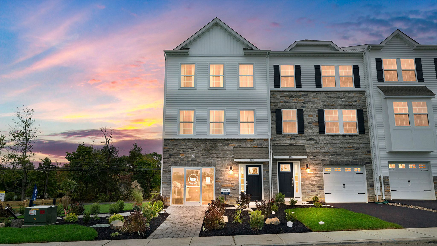 Exterior back image of a three story townhome with white horizontal paneling, the second story balcony, and the first floor back sliding glass door.