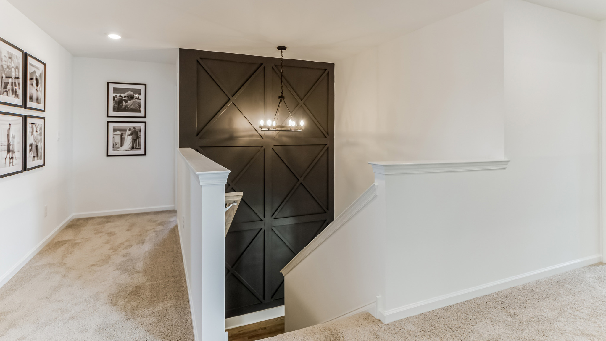Top of the stairs on the second flooring with hallways going to the left and straight which enters the laundry room.