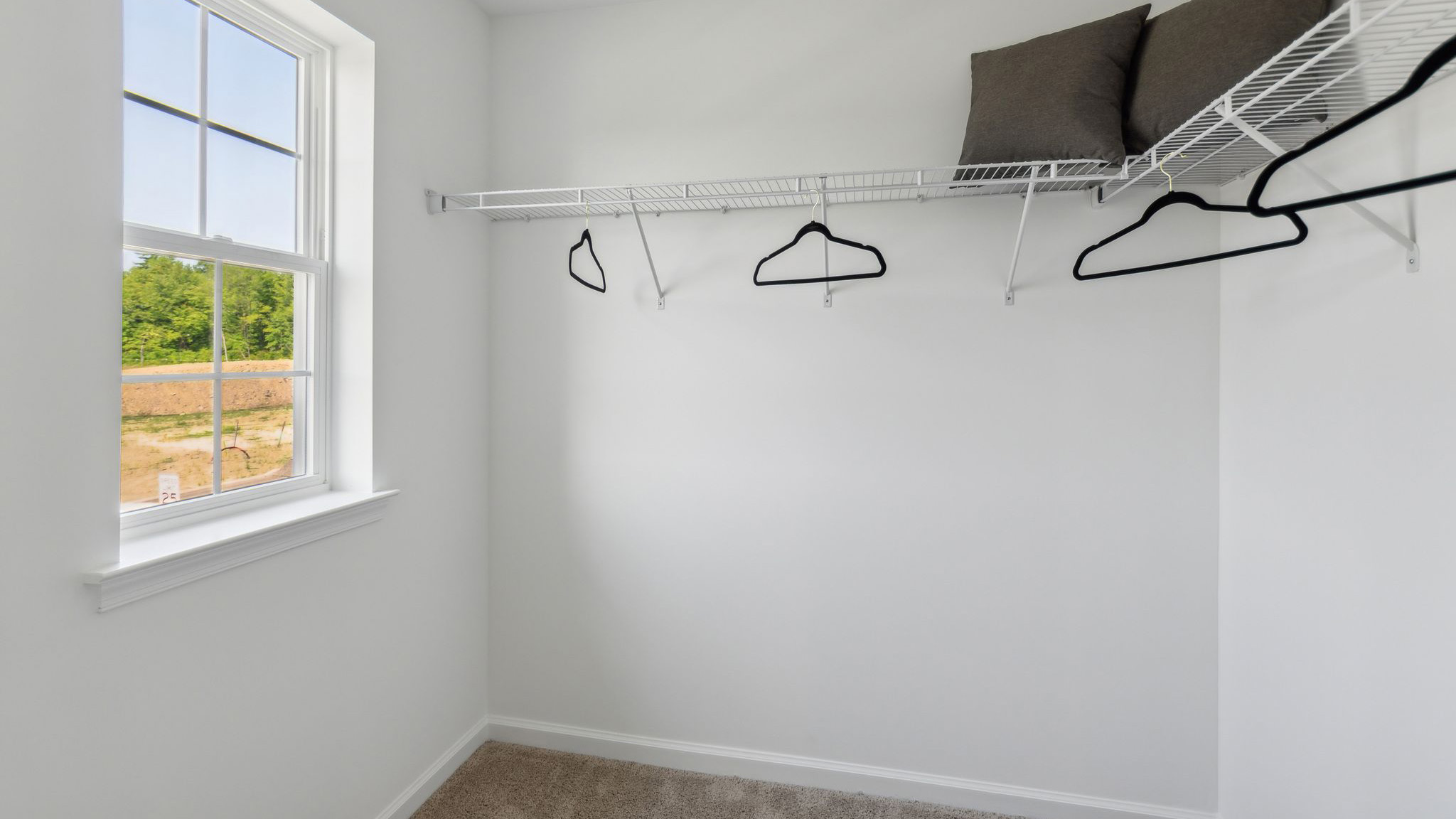 Large closet with racks and shelves and single window.