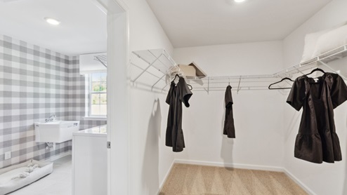 Other side of the large primary closet with peek into the laundry room.