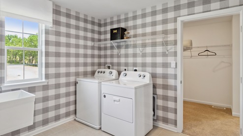 Different view of the laundry room with a peek into the other side of the primary closet.
