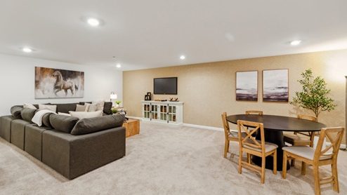 Different view of the large finished basement area with couch, tv, and table.