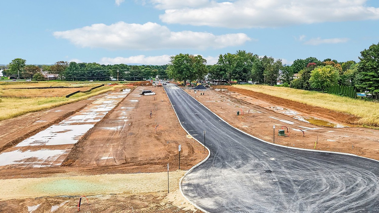 An aerial view looking down on the Farmhouse community with just the roadway and curbs completed