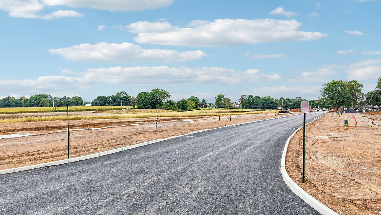 An aerial view looking down on the Farmhouse community with just the roadway and curbs completed