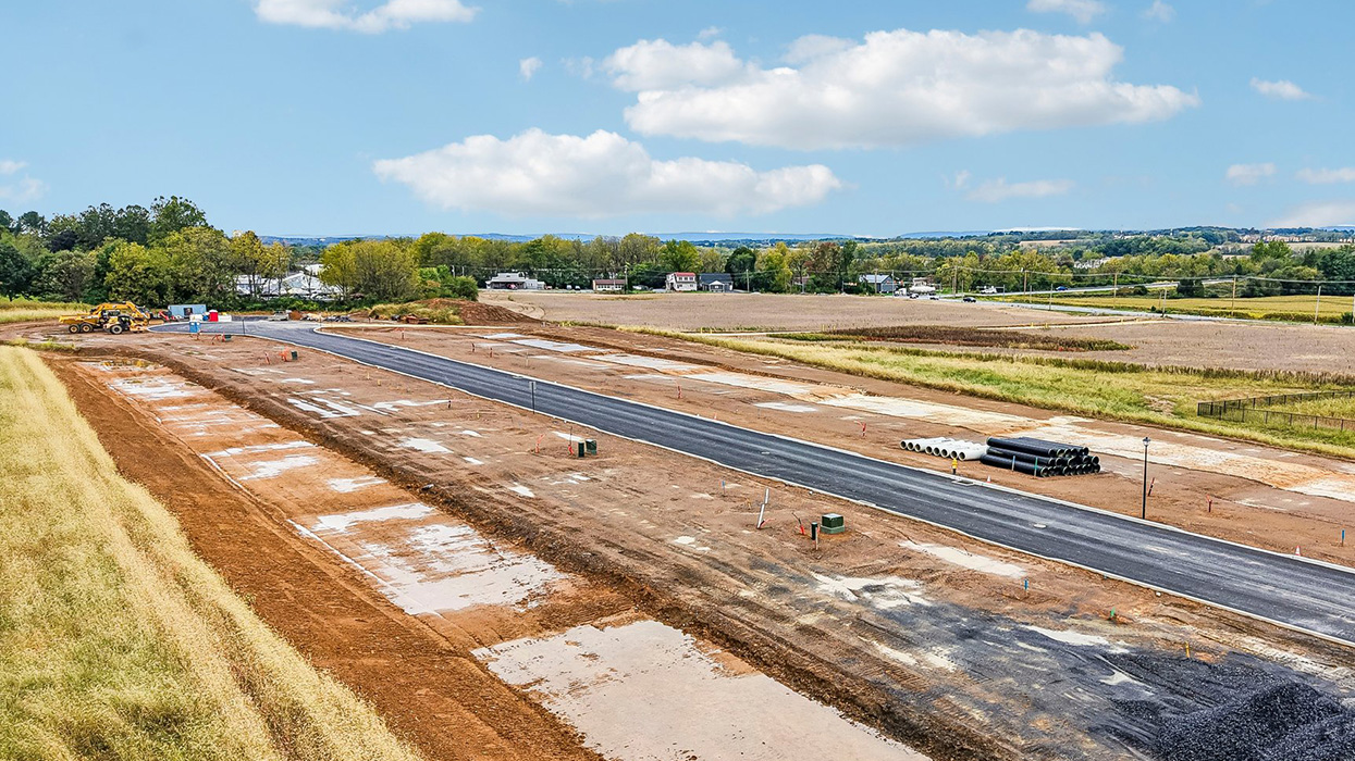 An aerial view looking down on the Farmhouse community with just the roadway and curbs completed