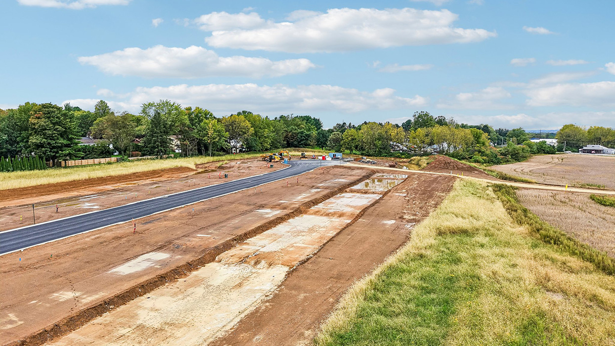 An aerial view looking down on the Farmhouse community with just the roadway and curbs completed