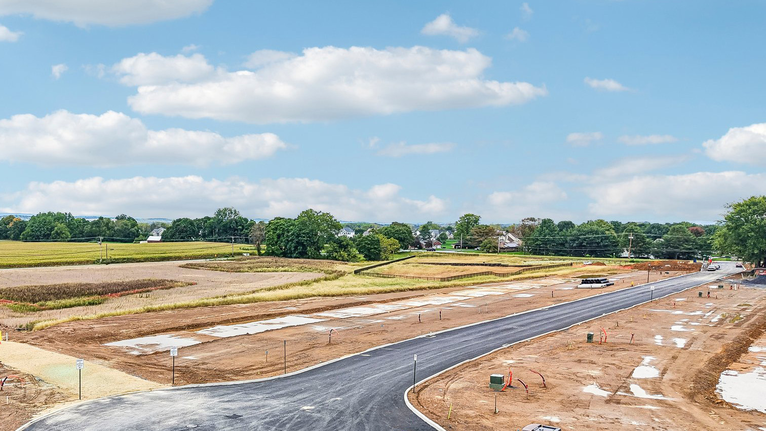 An aerial view looking down on the Farmhouse community with just the roadway and curbs completed