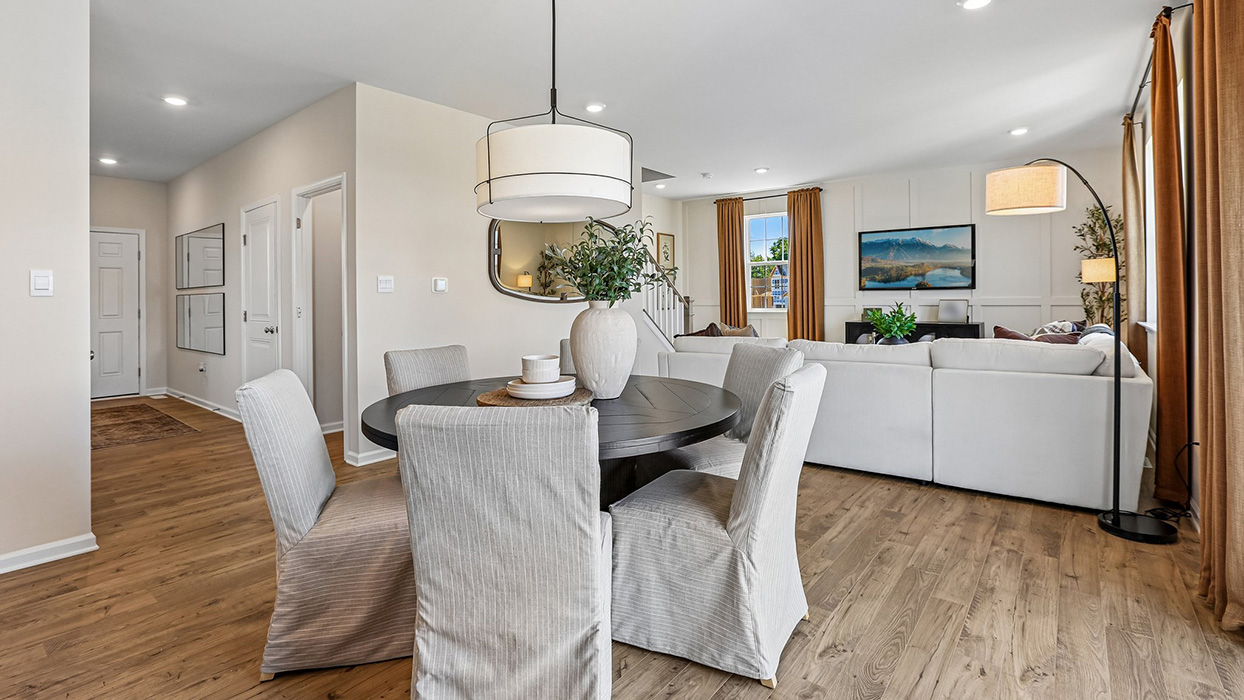 A wide angle view of the living area while looking past the dining area, foyer on the left side.