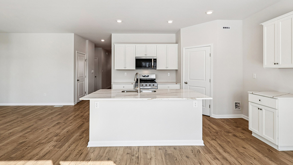 A straight on view of the large kitchen island with white kitchen cabinets on the wall behind and to the side