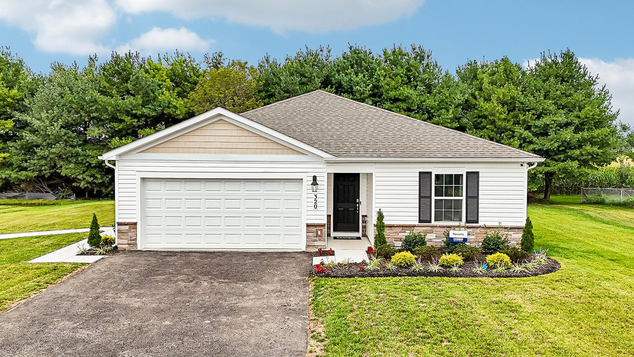 A Neuville ranch style home with white siding, sand shake accent siding, dakota ledgestone kneewall, black shutters, and a white garage door.