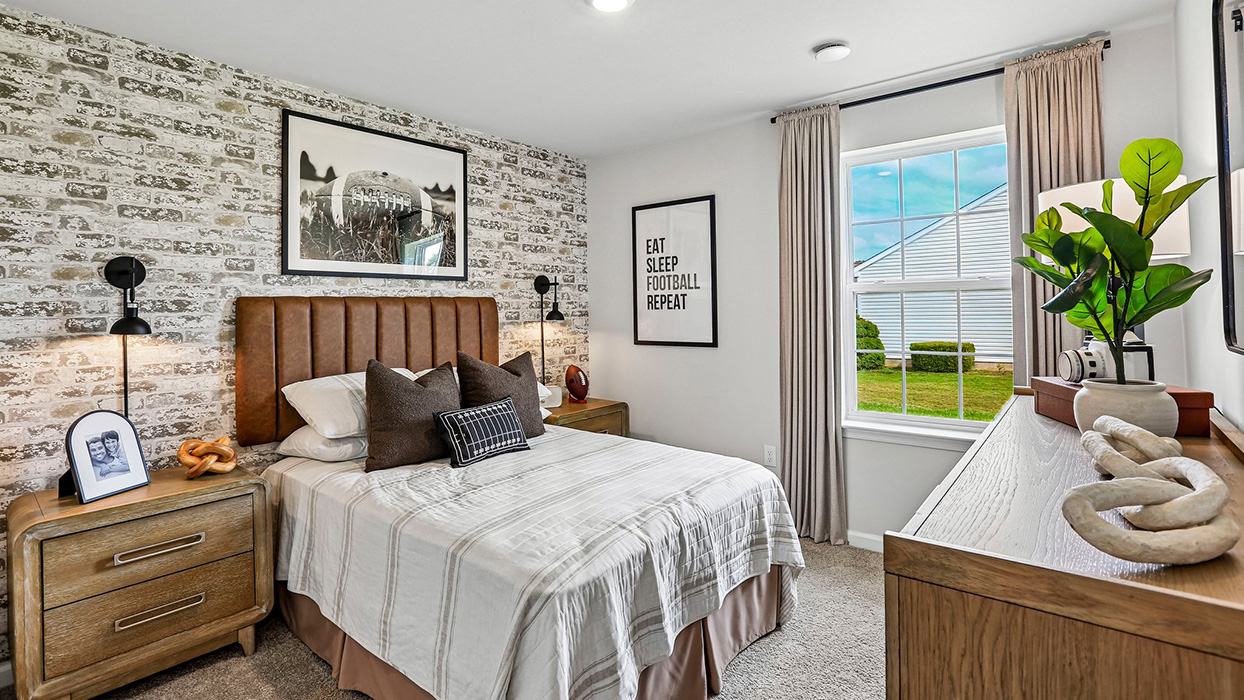 Secondary bedroom with cozy styling, accent wall design, and bedside lighting in a thoughtfully designed new home