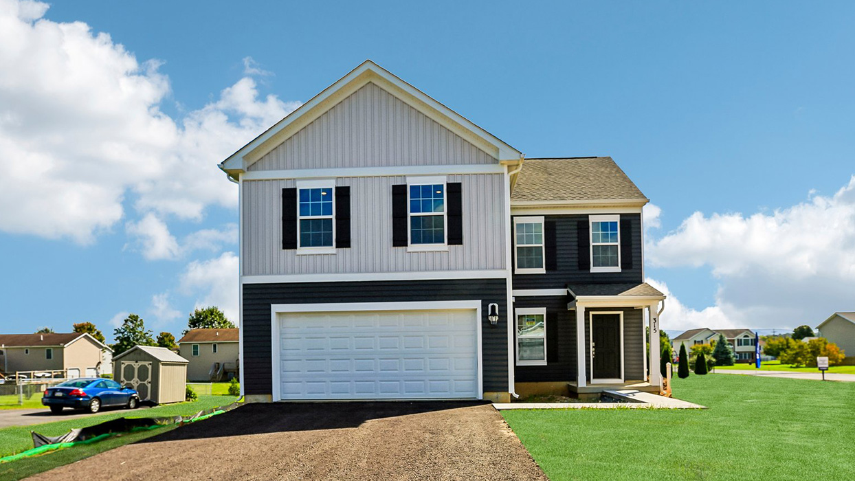 A front photo of a Deerfield home with wicker primary siding, midnight surf board and batten accent siding, and a white two car garage.