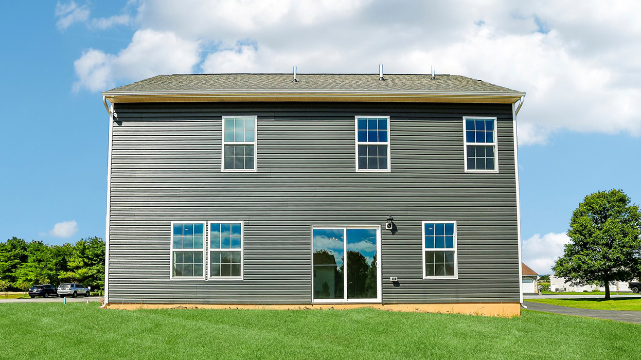 A rear photo of a Deerfield home with wicker primary siding, midnight surf board and batten accent siding, and a white two car garage.