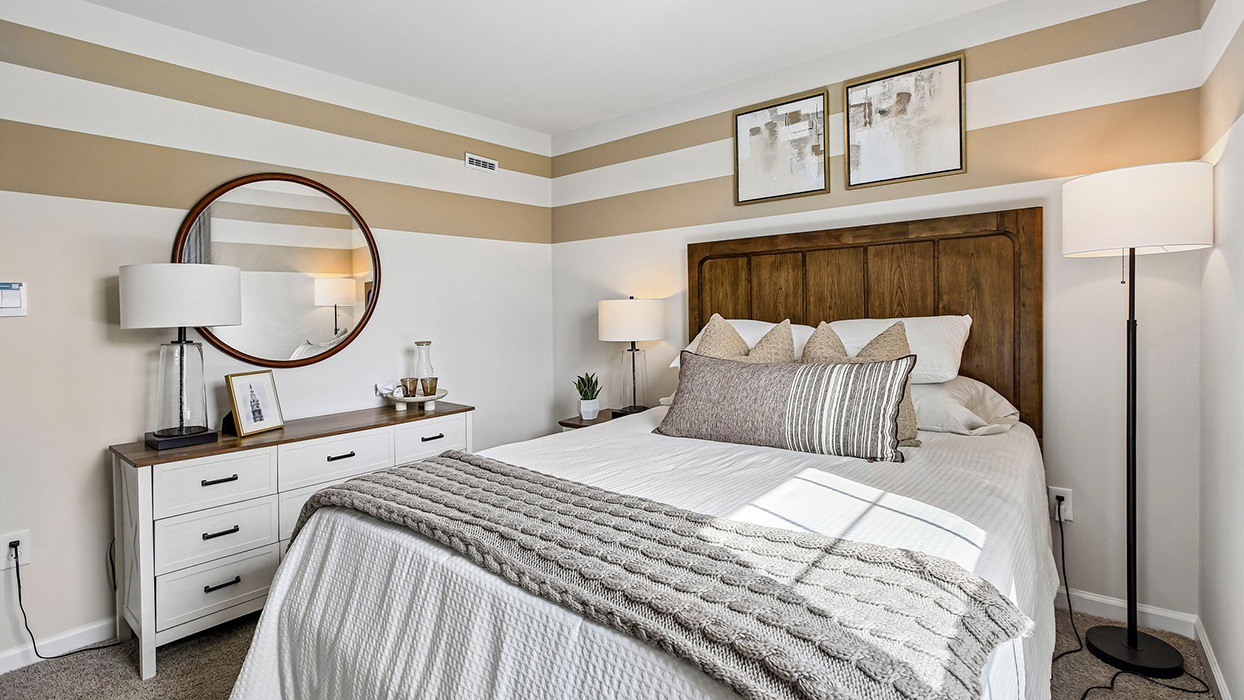 Bedroom in a new home with large window, plush carpeting, and soft neutral bedding filled with natural light