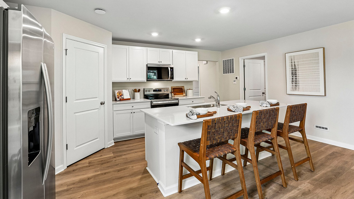 Kitchen with large island seating, white cabinetry, and stainless steel appliances