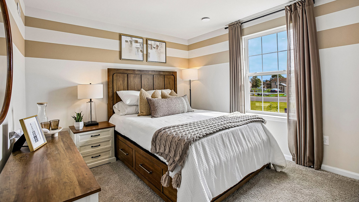 Bright bedroom featuring oversized window, soft carpet, and views bringing natural light into this new home