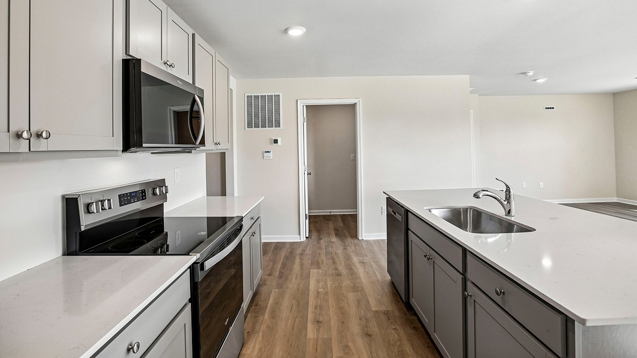 kitchen with gray cabinets and stainless steel appliances with a view toward the landry room